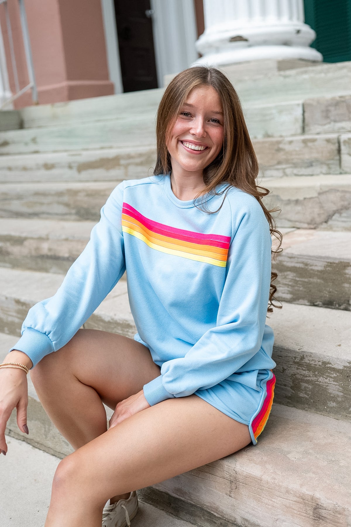 Woman wearing sweatshirt and short set sitting on steps