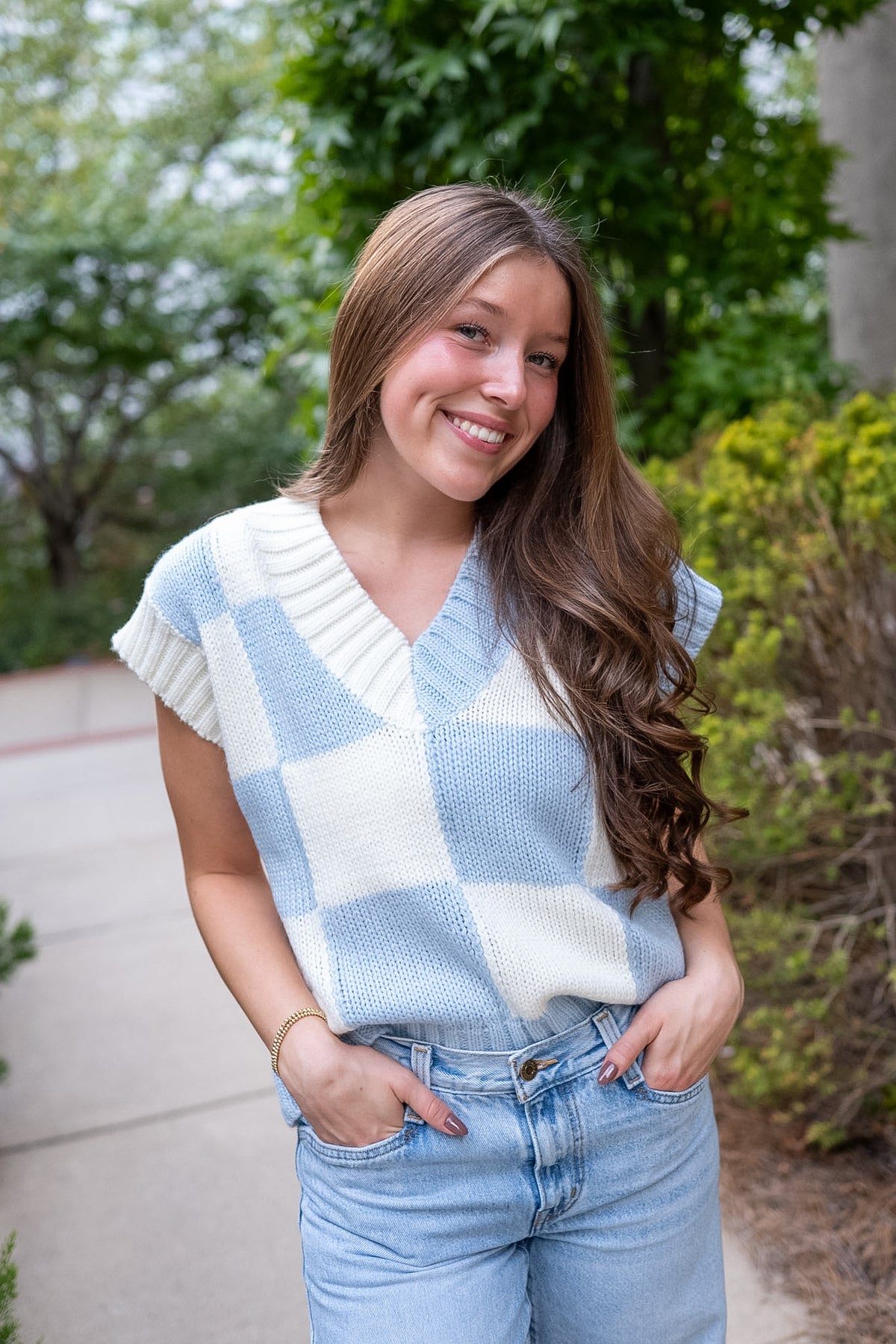 Girl wearing blue white checkerboard vest and blue jeans