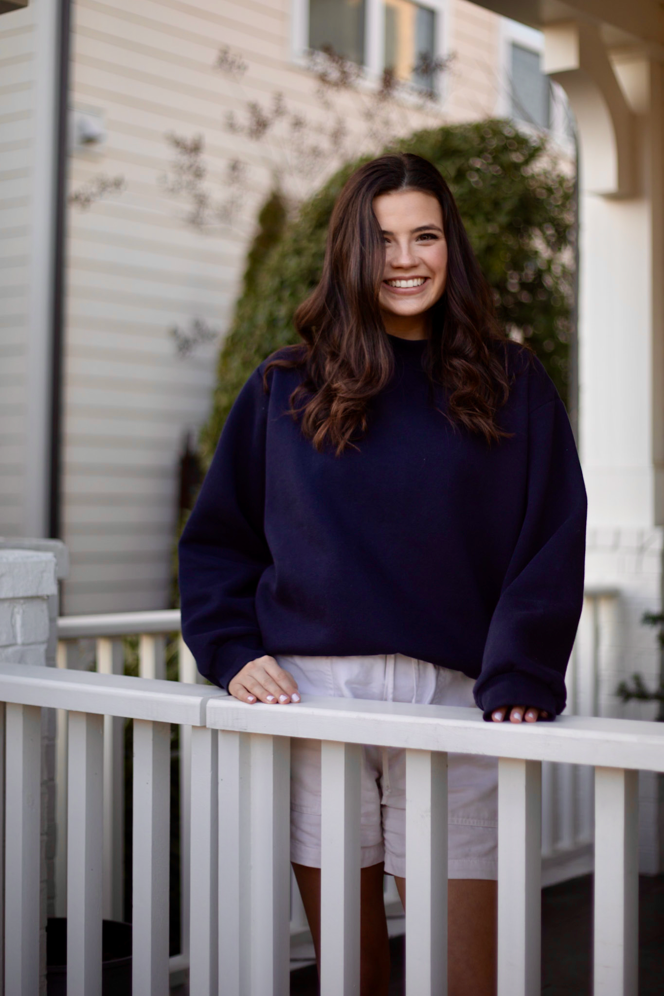 Lady standing on white porch in navy sweatshirt