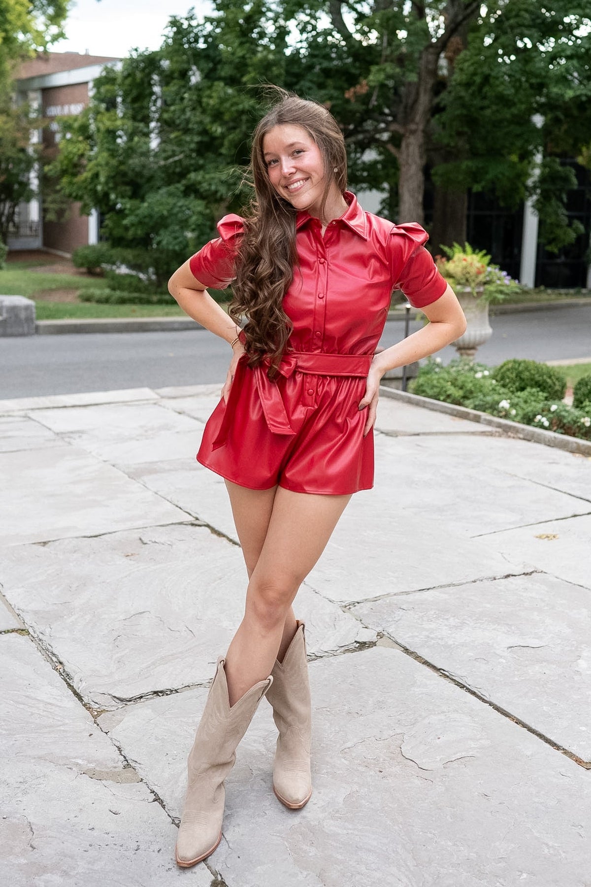 Lady wearing red faux leather shorts romper standing on limestone path