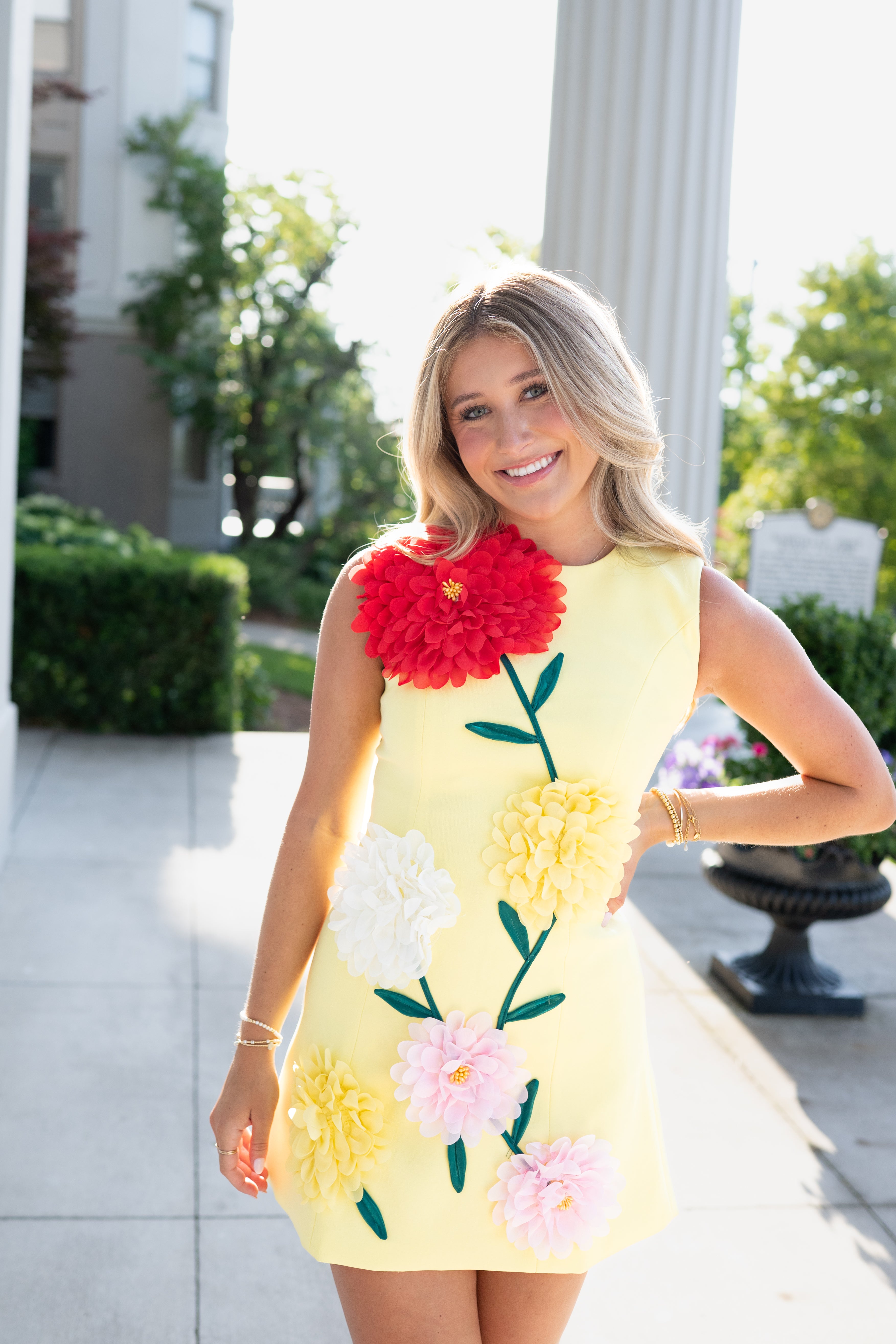 Woman wearing a yellow dress with floral designs outdoors