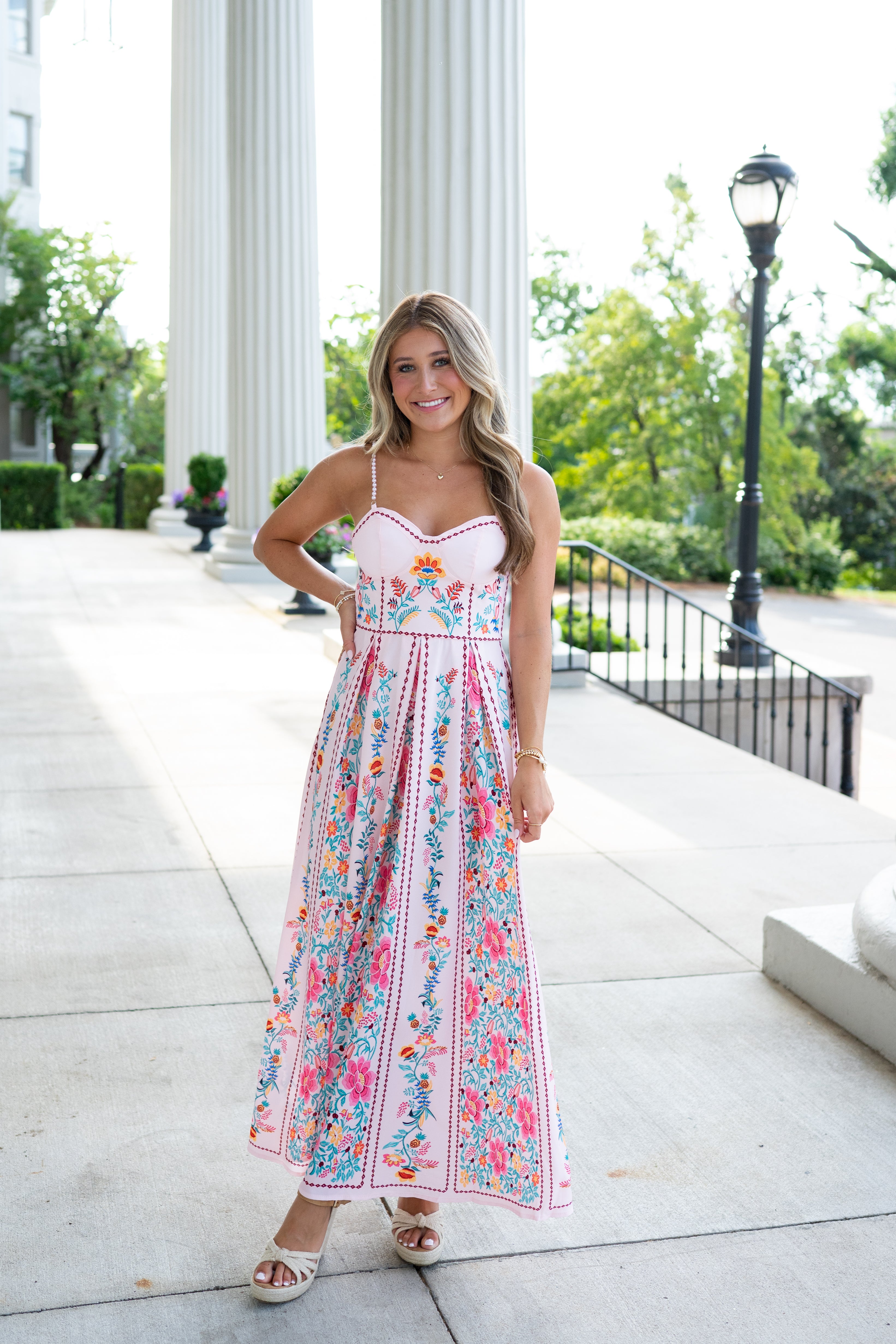 Woman in a floral dress standing outdoors with classical columns in the background