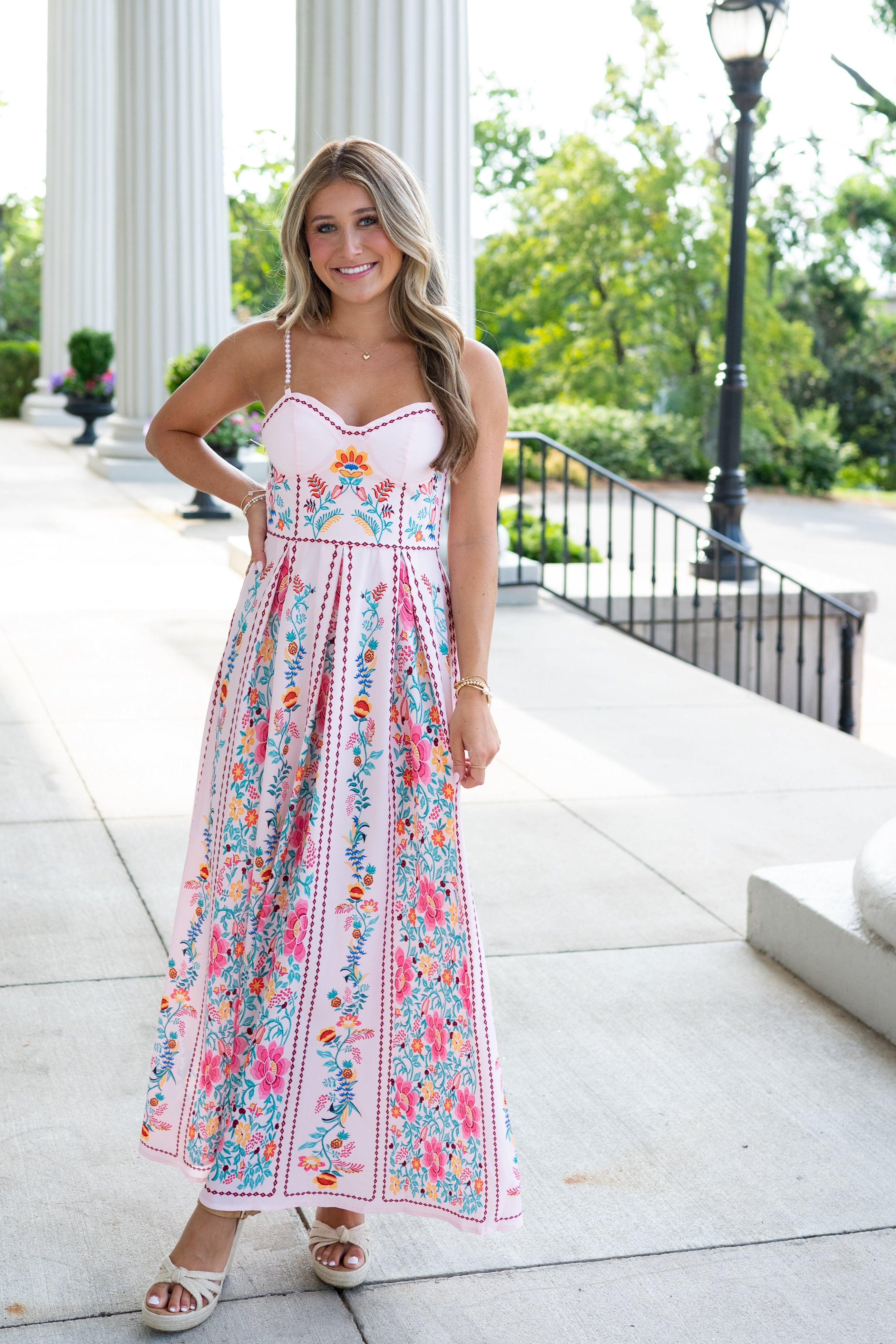 Woman in a floral dress standing outdoors with classical columns in the background
