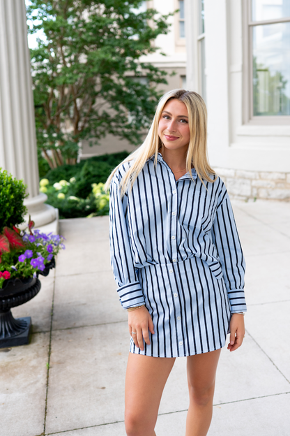 Woman wearing a blue and navy striped outfit standing outdoors.