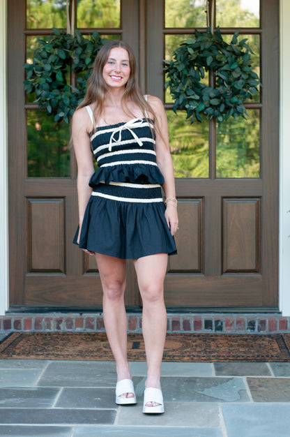 Woman in a black and white striped mini skirt set with rouched top and skirt band