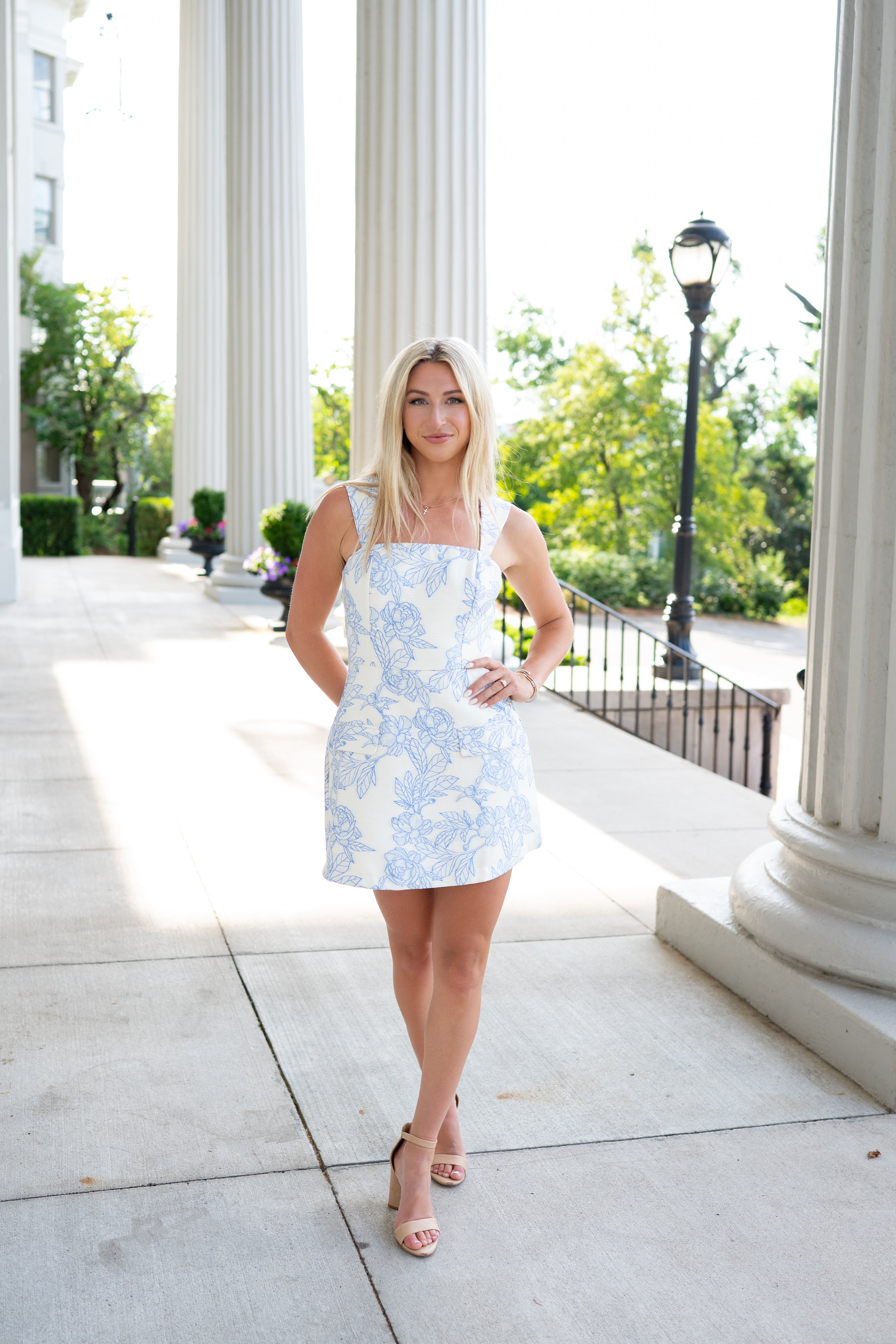 Woman in a light blue floral dress standing in front of classical columns.