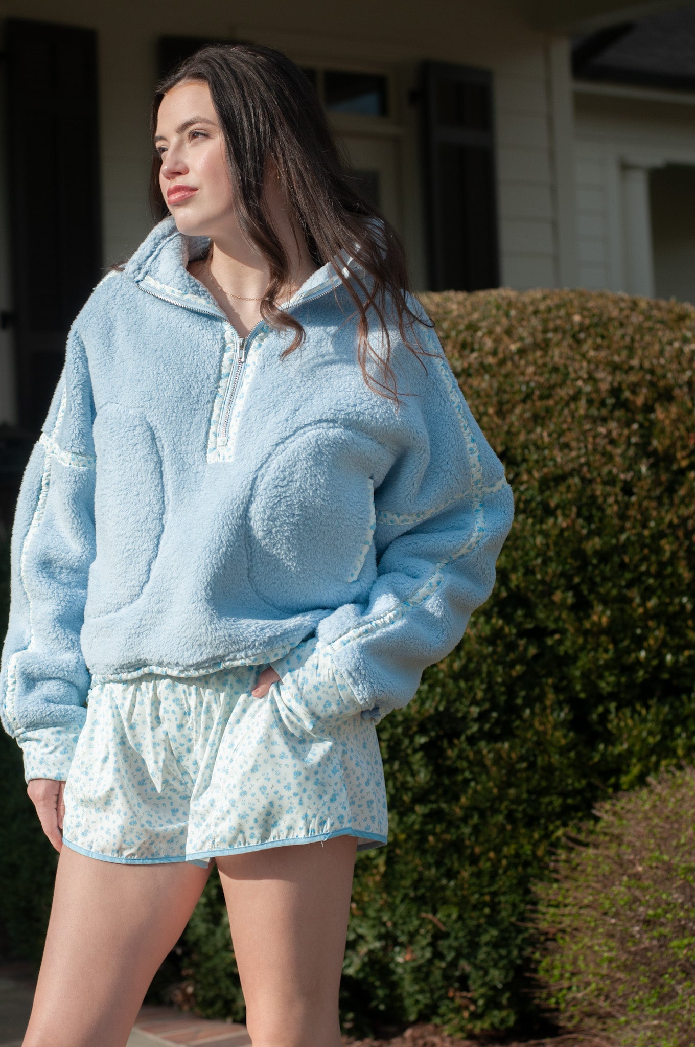Woman wearing a light blue fleece outfit standing outdoors.