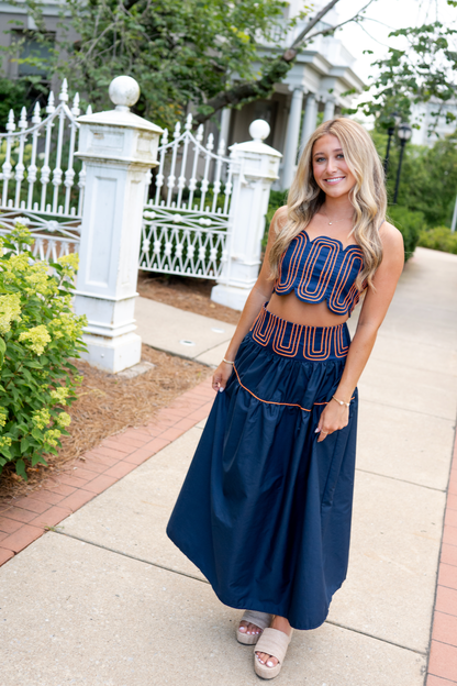 Woman wearing a navy and orange skirt set in an outdoor setting.