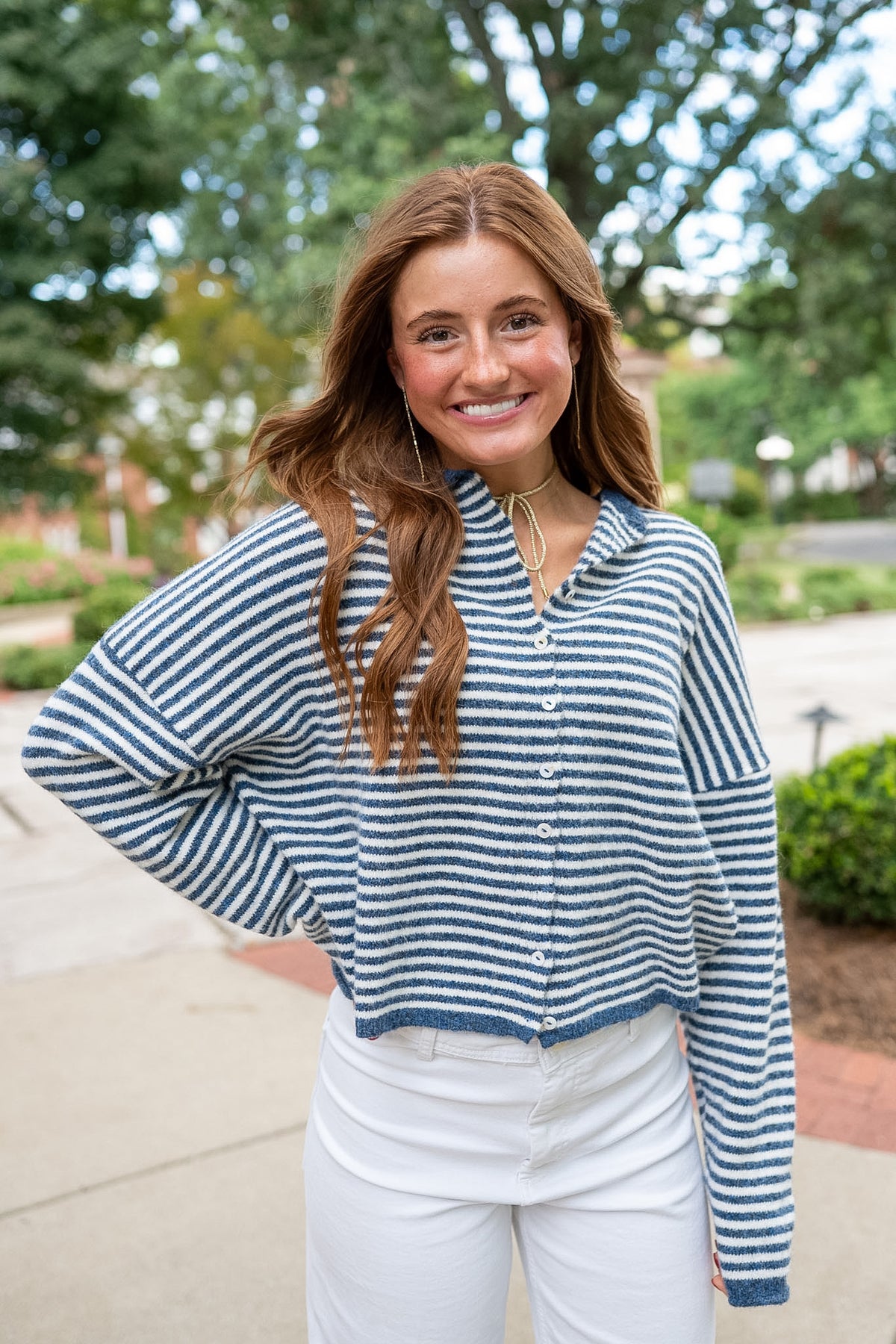 Woman wearing navy and white striped cardigan sweater and white jeans
