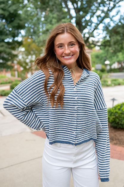 Woman wearing navy and white striped cardigan sweater and white jeans