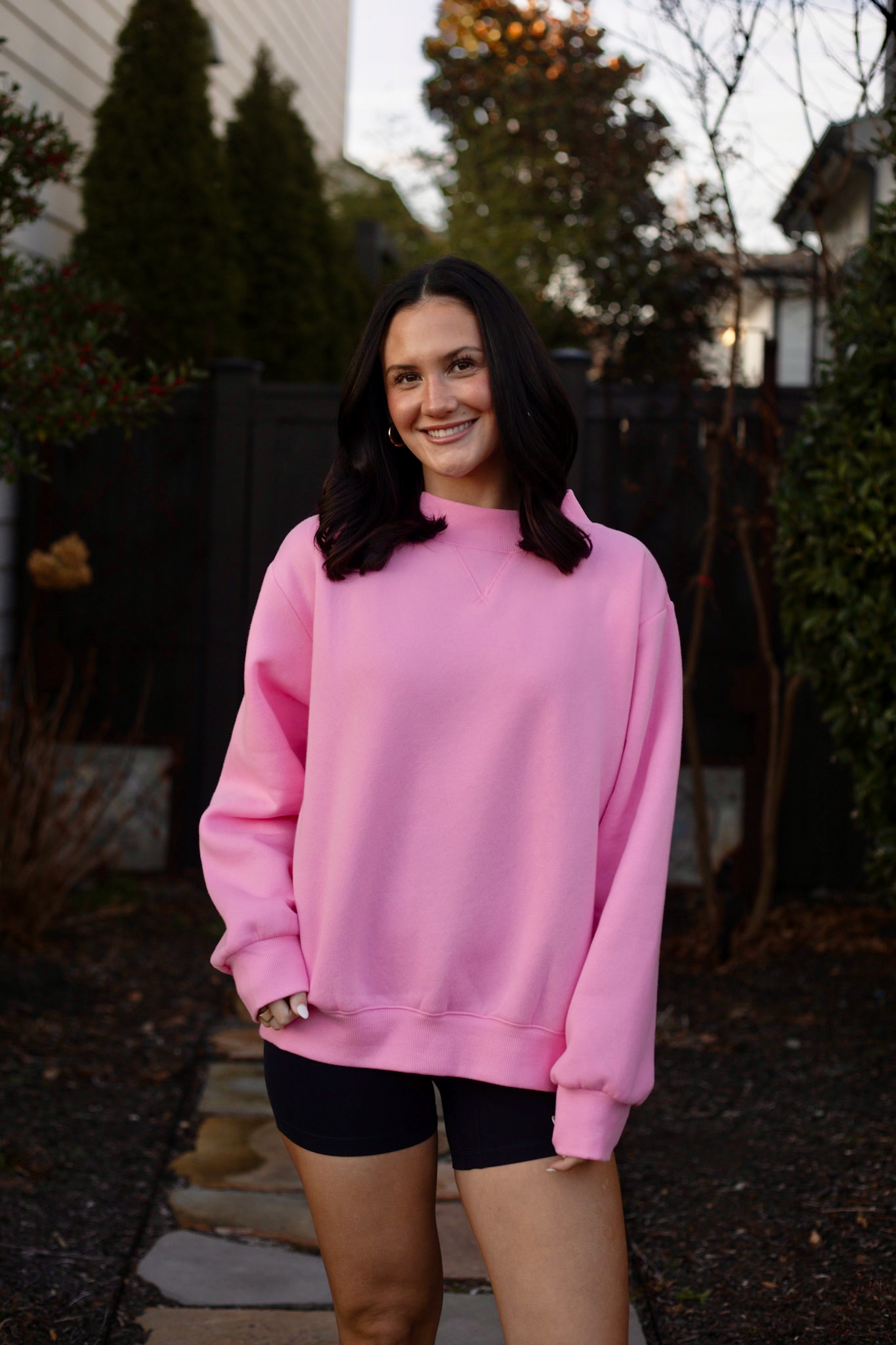 Lady wearing pink sweatshirt standing in a garden