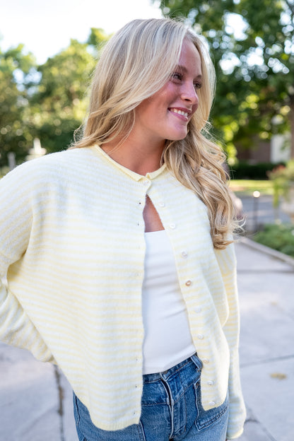 Woman wearing yellow white striped cardigan and blue jeans 