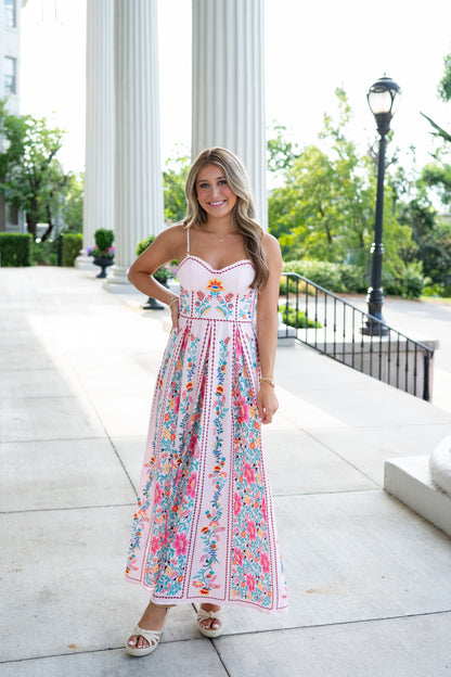 Woman in a floral dress standing outdoors with classical columns in the background